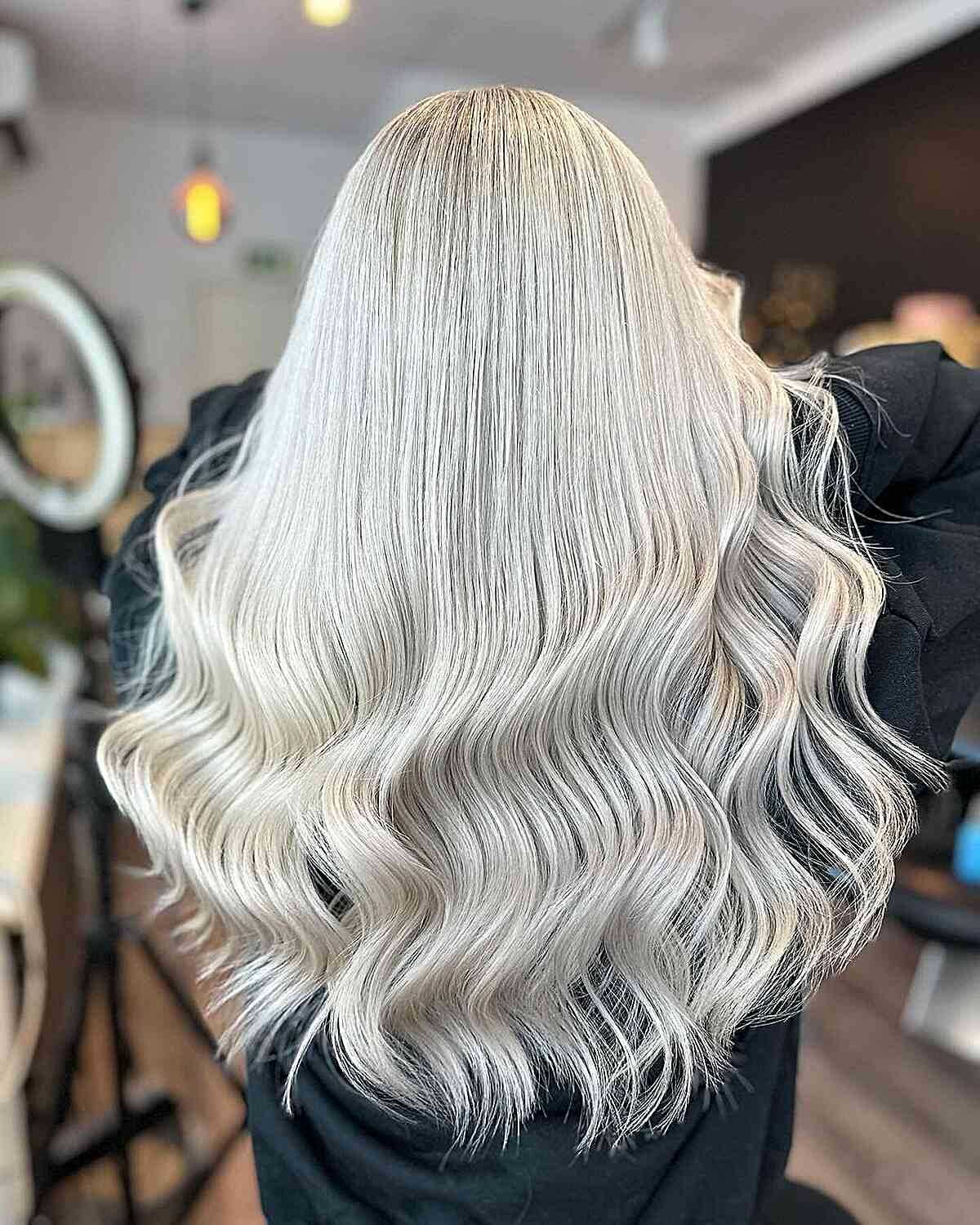 Woman with long, wavy, platinum blonde hair in a salon, showcasing a fresh, stylish hair color.