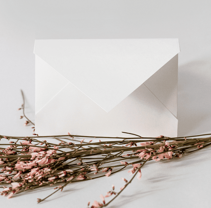 White envelope with pink dried flowers on a light background.